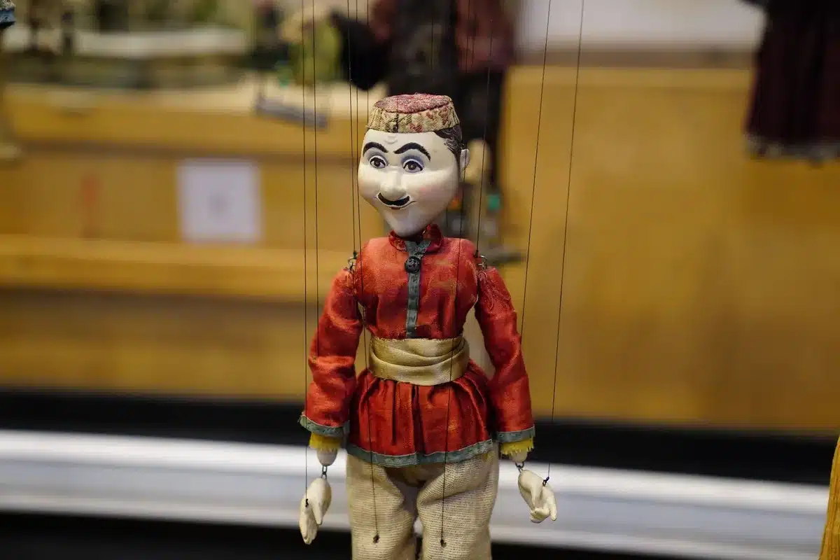 Mains examinant avec soin une poupée vintage, ses vêtements et sa boîte d'origine