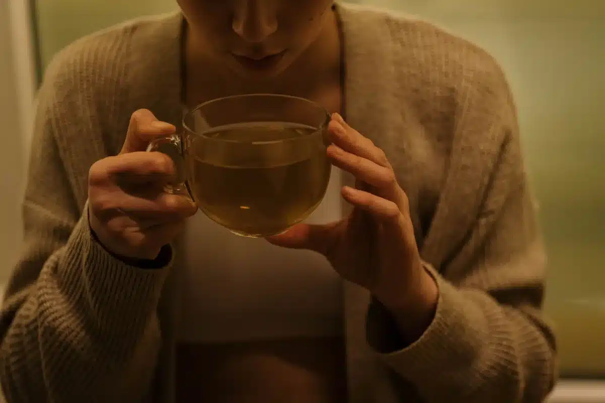 Femme assise confortablement avec une tasse de tisane chaude en fin de journée