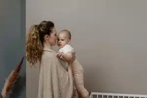 Mains d'un adulte réconfortant tendrement un nourrisson dans une ambiance calme et lumineuse.