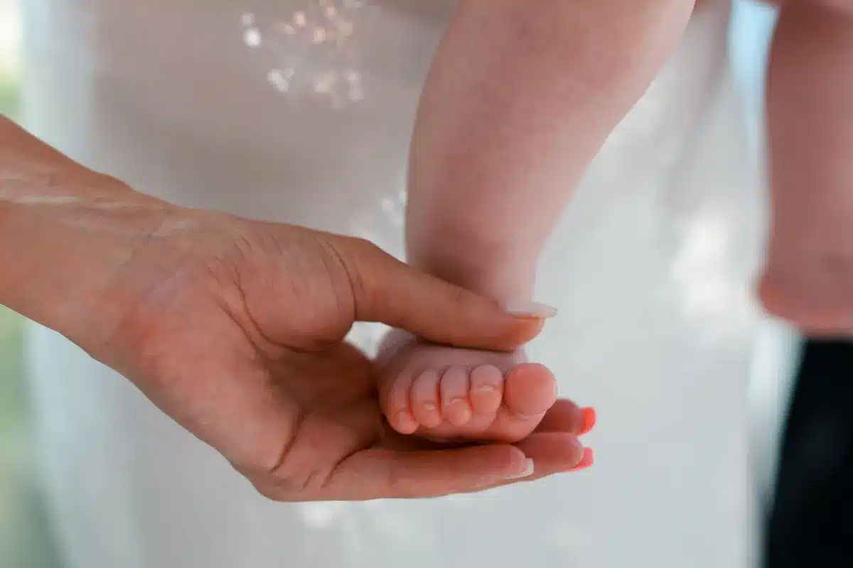 Main d'un parent touchant délicatement la nuque d'un bébé pour vérifier sa température