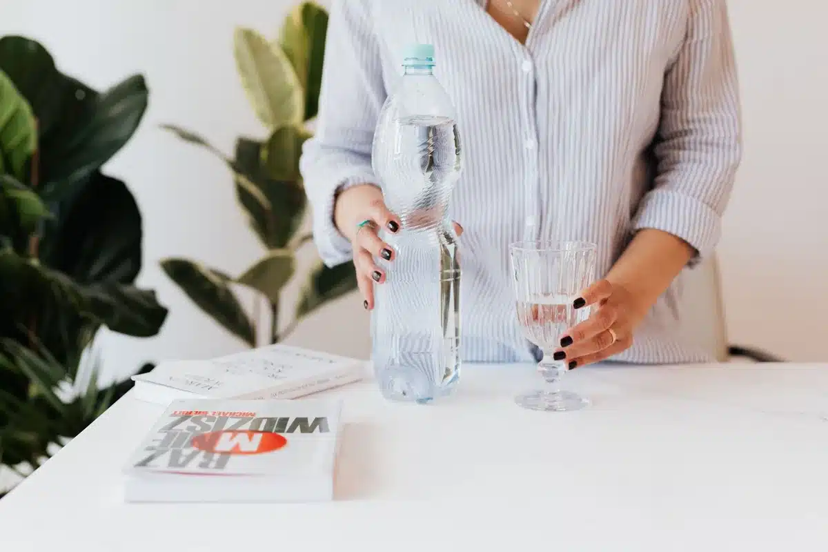 Bouteille d'eau réutilisable posée sur un bureau ou une surface de travail, rappelant l'importance de boire régulièremen