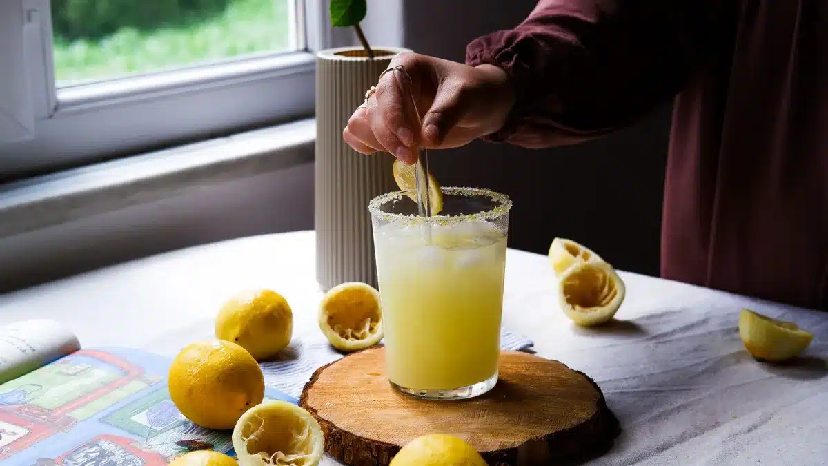 Un verre de shot de gingembre fumant avec des tranches de gingembre frais et citron