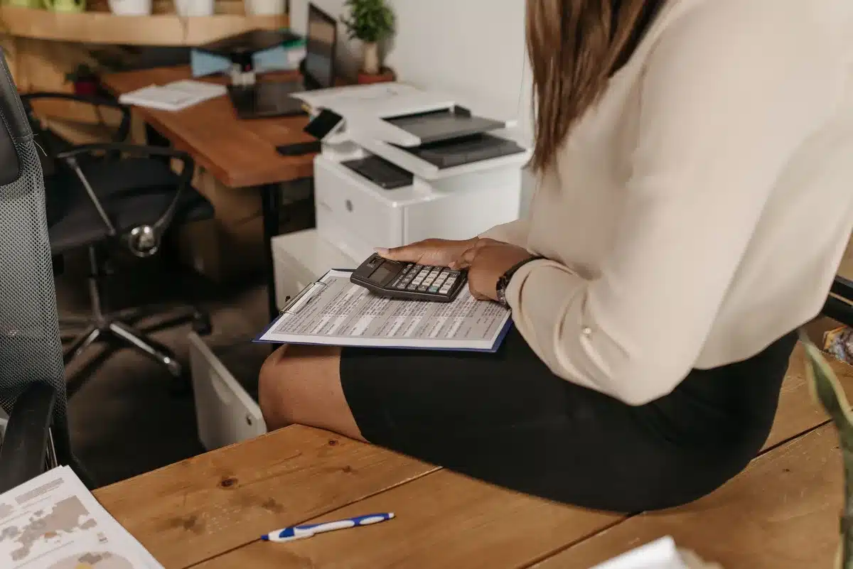 Personne examinant une facture médicale et des documents d'assurance à un bureau avec une calculatrice
