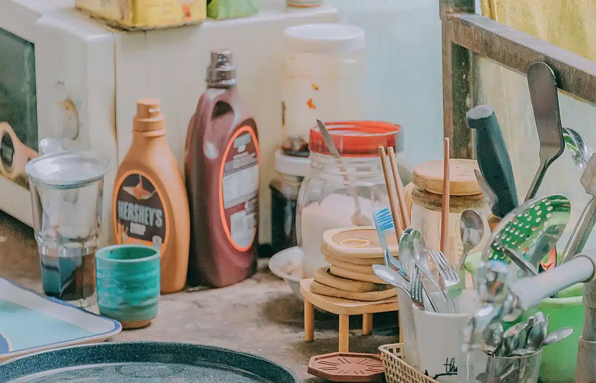 Mains tenant une bouteille d'eau et un biberon sur un plan de travail de cuisine