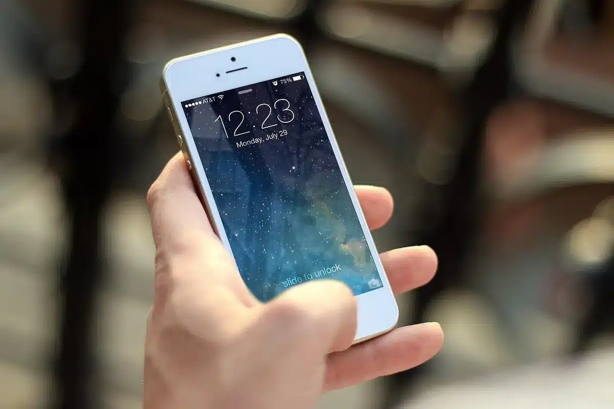 Mains tenant un smartphone affichant des commentaires sur les réseaux sociaux