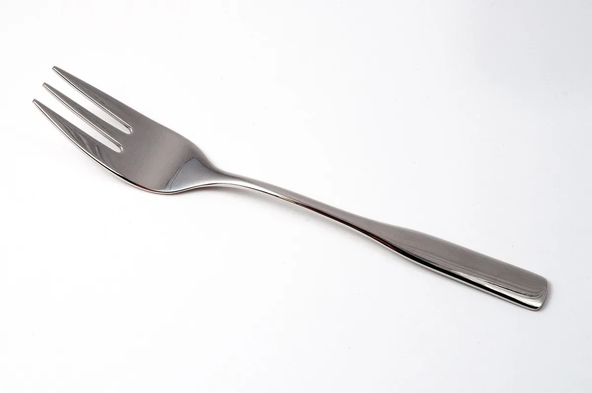 Personne posant sa fourchette entre deux bouchées à table (visage non visible)