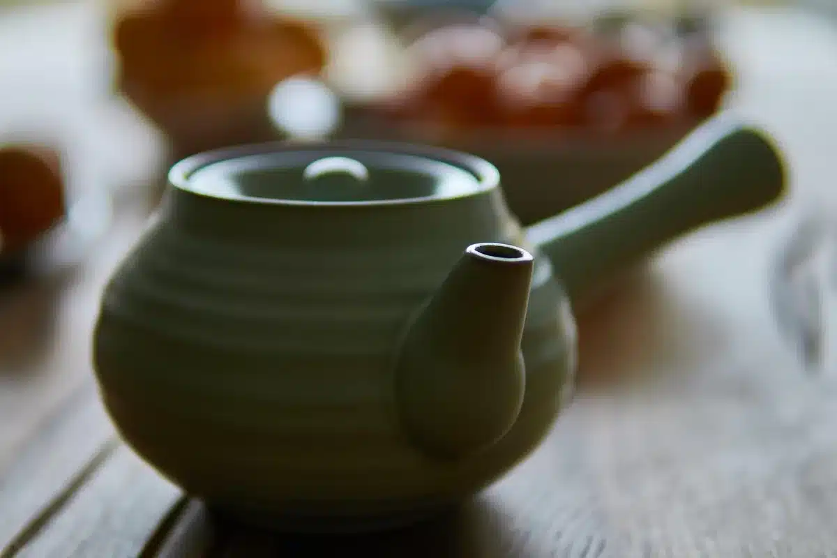Thé kukicha en tasse et brindilles sur table en bois près d'une fenêtre en plein jour